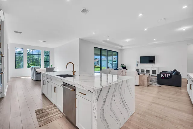 a large kitchen with stainless steel appliances granite countertop a lot of counter space and a wooden floor