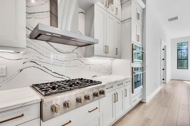 a kitchen with stainless steel appliances a stove oven and white cabinets with wooden floor