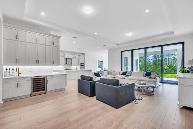 a living room with furniture large windows and wooden floor