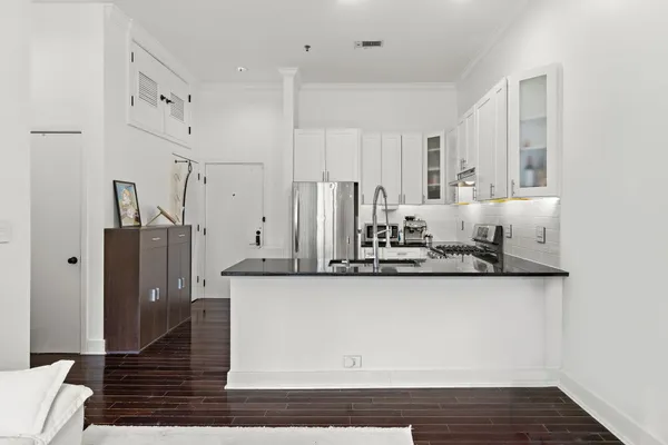 a kitchen with stainless steel appliances granite countertop a stove top oven a sink dishwasher and white cabinets with wooden floor