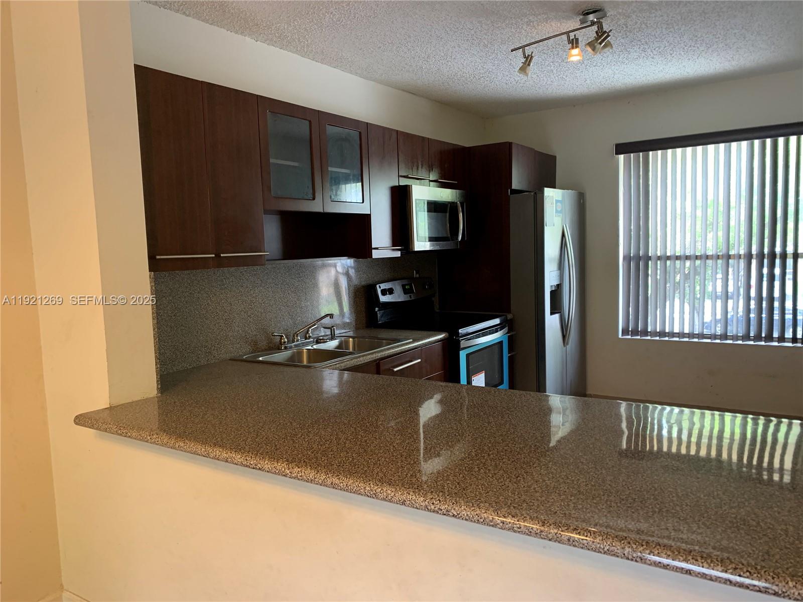 2171 Southwest 80th Terrace, Unit 2171 Miramar, FL 33025 - Photo 2 of 7 a kitchen with stainless steel appliances granite countertop a refrigerator a stove and a sink with wooden floor