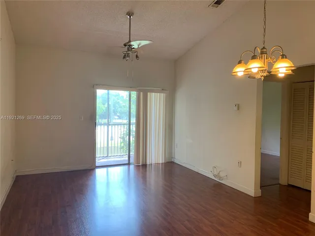 a view of a room with wooden floor chandelier and windows