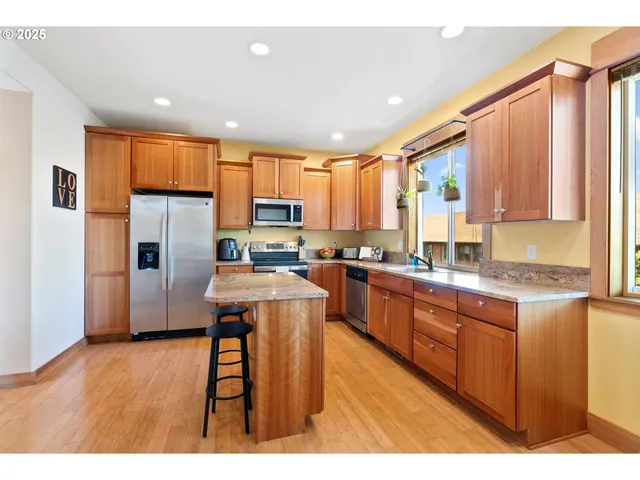 a kitchen with stainless steel appliances granite countertop a refrigerator a sink dishwasher a stove and white countertops with wooden floor