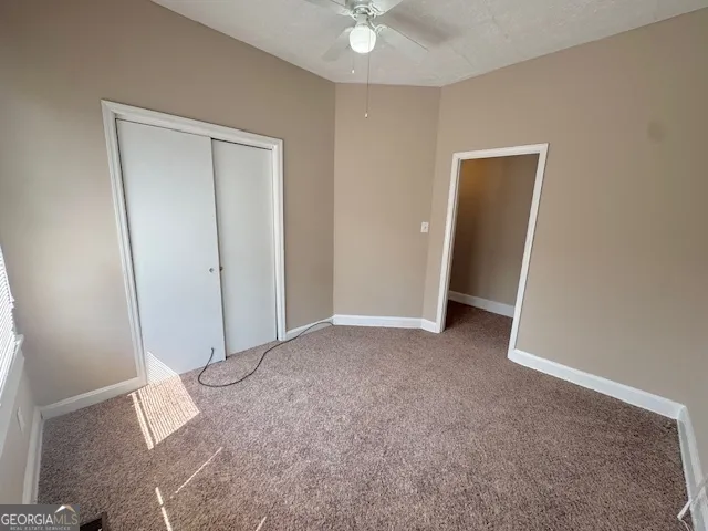 an empty room with closet and fan