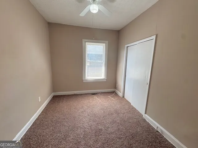 an empty room with windows and fan