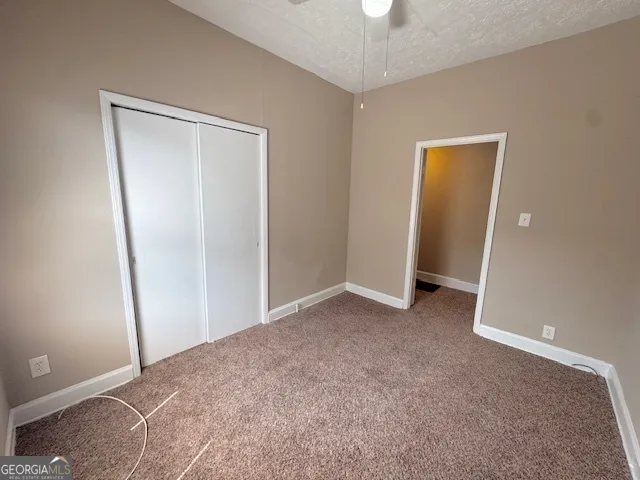an empty room with closet and a chandelier fan