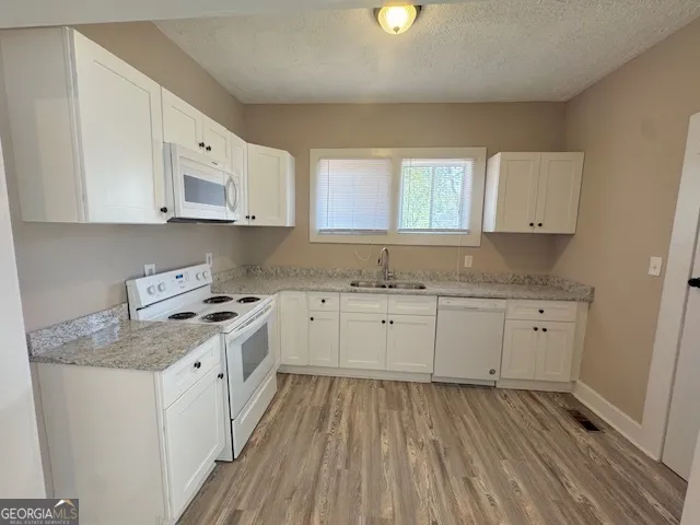 a kitchen with granite countertop white cabinets sink and stainless steel appliances