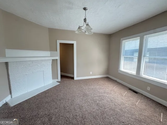 an empty room with chandelier fan and windows