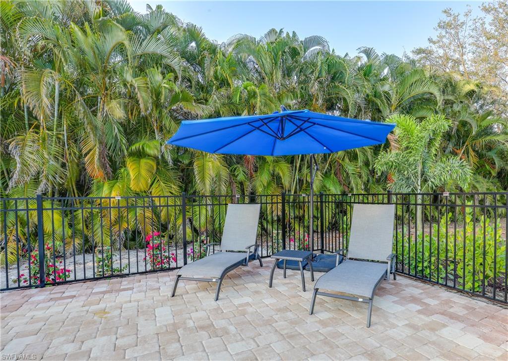 2708 Santa Cruz Boulevard Naples, FL 34112 - Photo 29 of 38 a view of a patio with a table and chairs under an umbrella