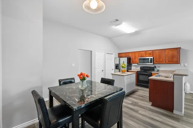 a kitchen with stainless steel appliances granite countertop a kitchen island hardwood floor sink stove dining table and chairs