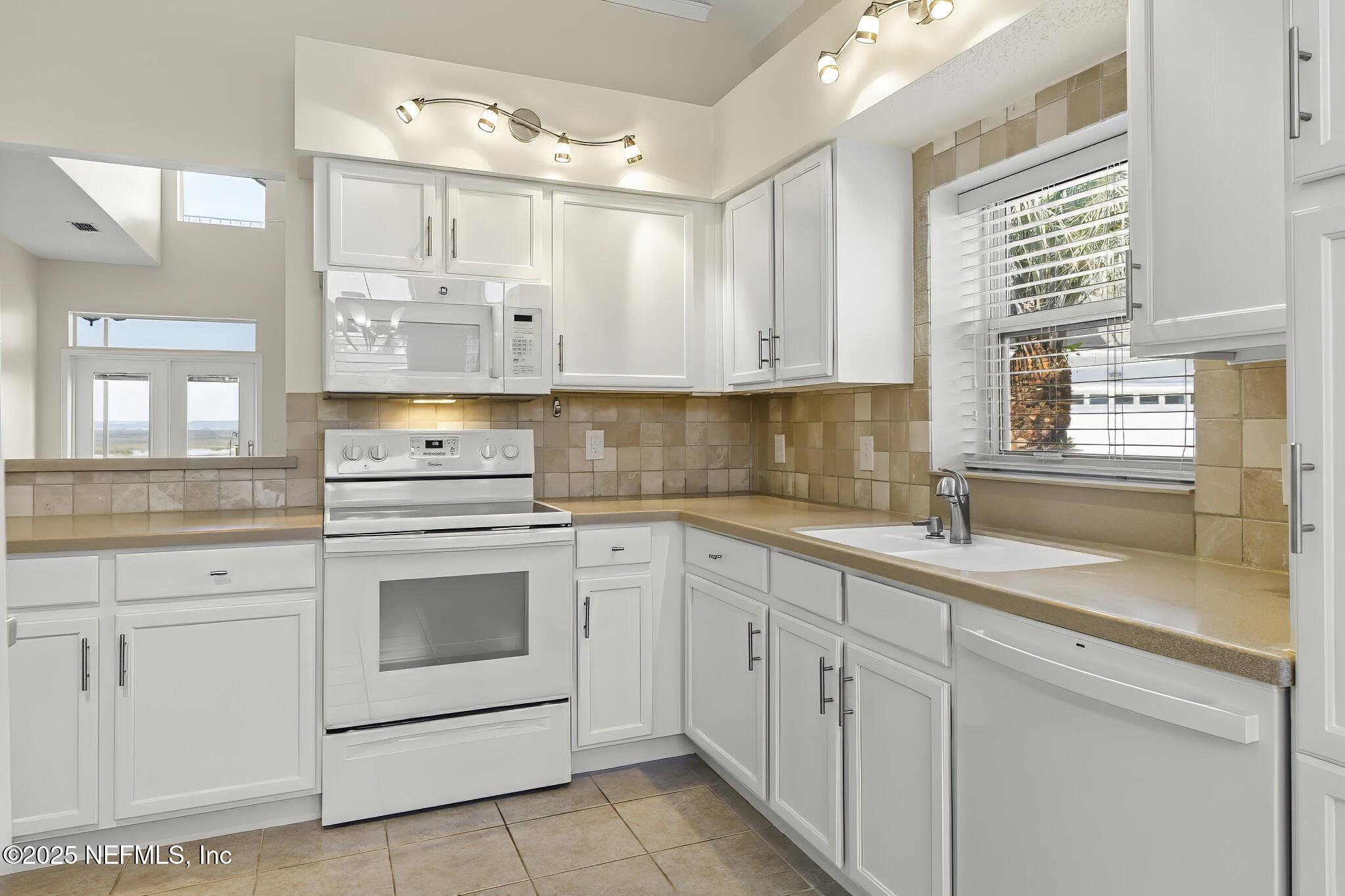 180 Kingston Drive St. Augustine, FL 32084 - Photo 14 of 55 a kitchen with white cabinets white appliances and sink