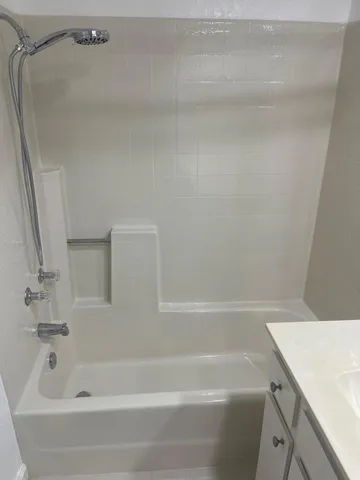 a white bath tub sitting next to a white sink and vanity