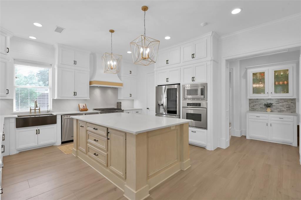 4111 Angling Lane Spring, TX 77386 - Photo 3 of 27 Kitchen with stainless steel appliances, suspended lighting, light wood finished floors, a center island, and two tone color scheme
