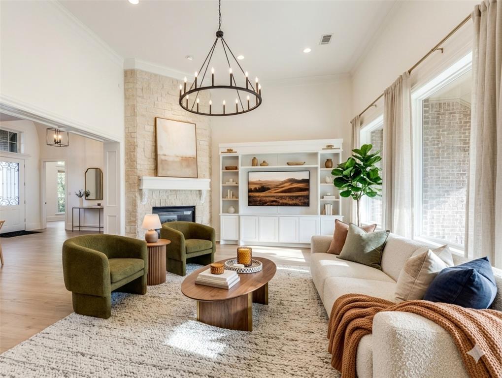 4111 Angling Lane Spring, TX 77386 - Photo 4 of 27 Living room featuring a chandelier, a stone fireplace, light wood finished floors, and crown molding (Digital Staging Used)