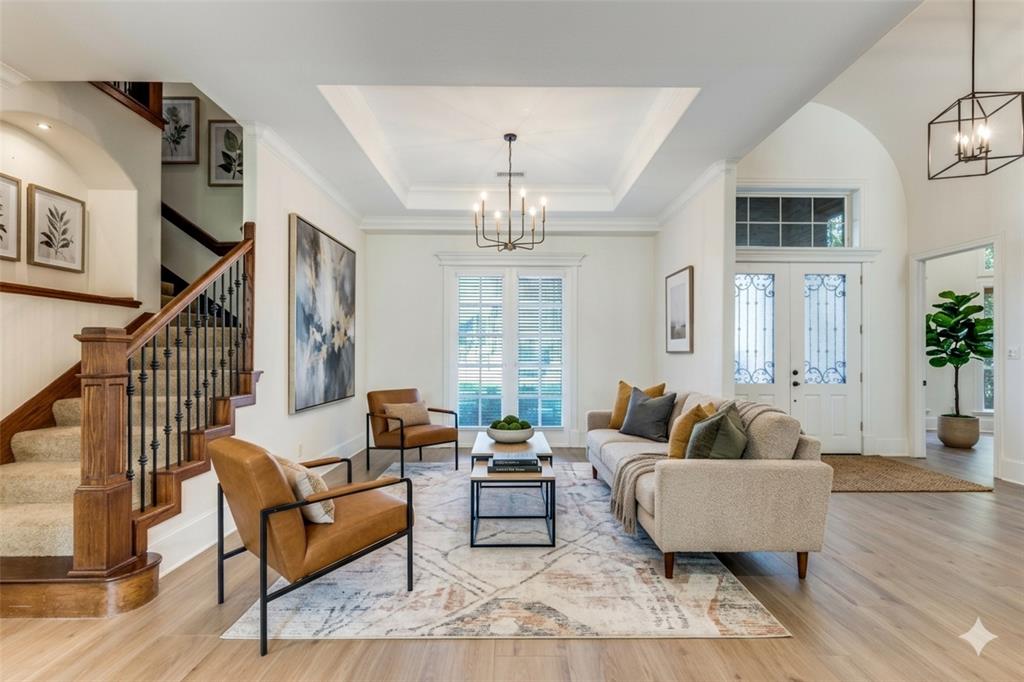4111 Angling Lane Spring, TX 77386 - Photo 6 of 27 Living room featuring suspended lighting, a raised ceiling, light wood-type flooring, french doors, and crown molding (Digital Staging Used)