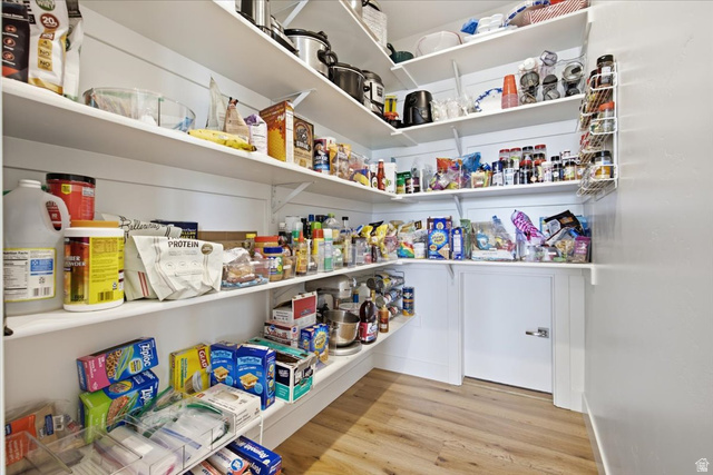 21 Pier Place Tooele, UT 84074 - Photo 30 of 112 Spacious walk-in pantry featuring white shiplap walls, extensive built-in shelving, durable wood-finish flooring, and a low-profile white door