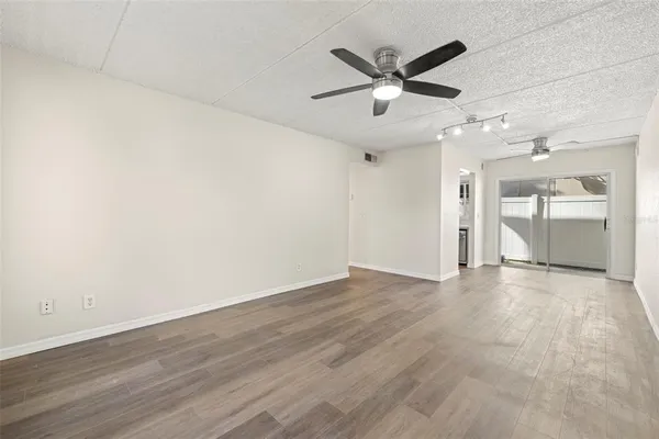 an empty room with wooden floor and a ceiling fan