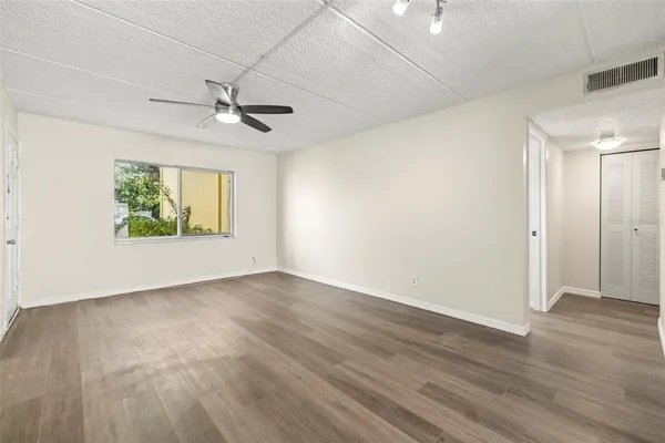 an empty room with wooden floor ceiling fan and windows