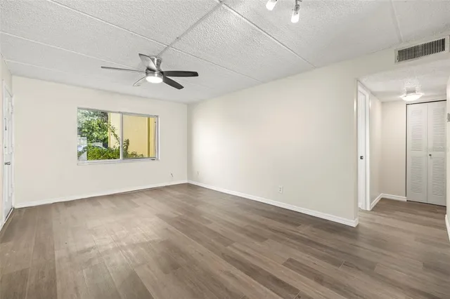 an empty room with wooden floor ceiling fan and windows