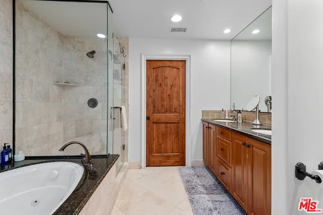 a bathroom with a granite countertop tub sink shower and mirror