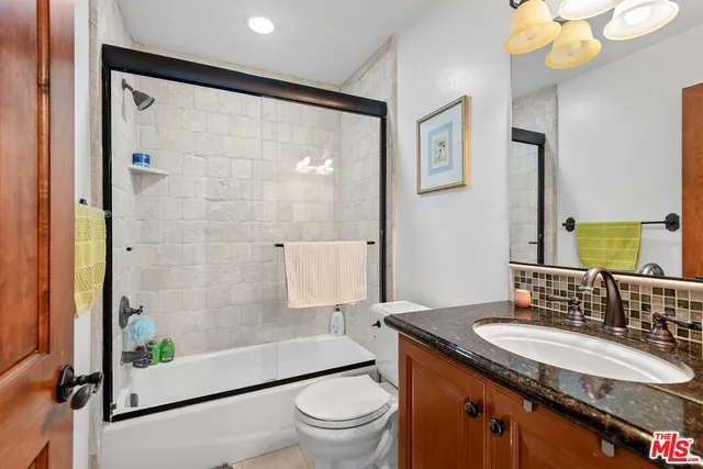 a bathroom with a granite countertop sink toilet a mirror and shower