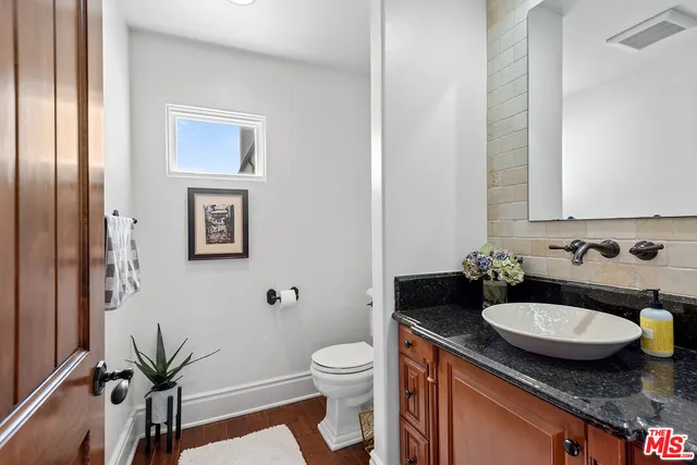 a bathroom with a granite countertop sink toilet and a mirror
