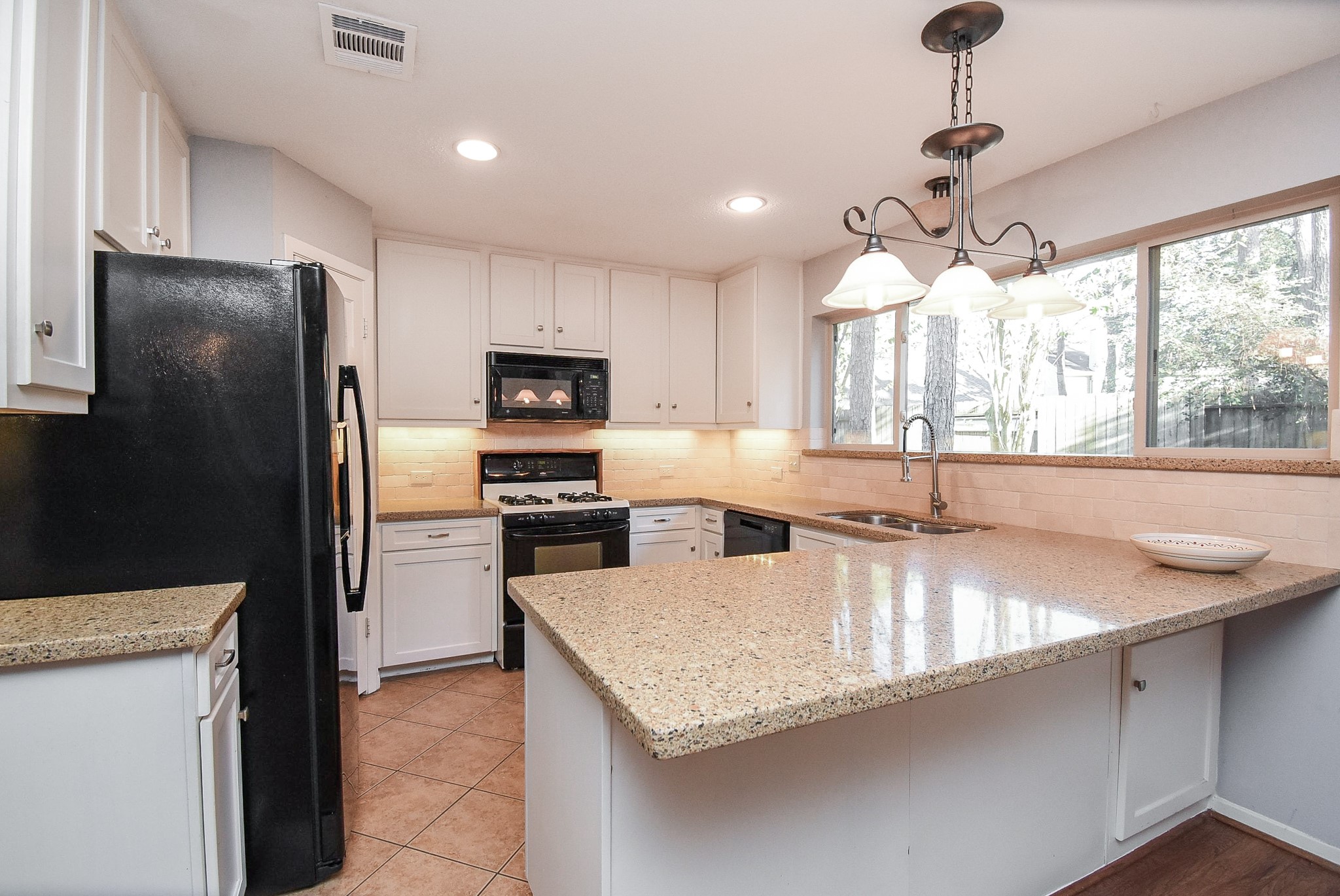 9107 Wallingham Court Spring, TX 77379 - Photo 12 of 25 a kitchen with stainless steel appliances granite countertop a sink a stove and a refrigerator
