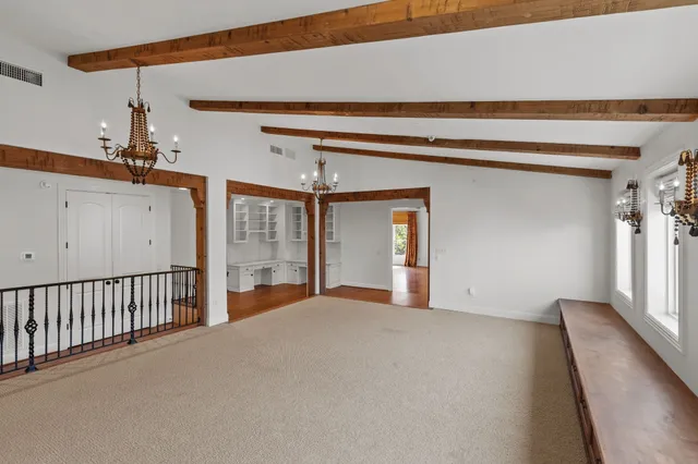 a view of an empty room with wooden floor and window