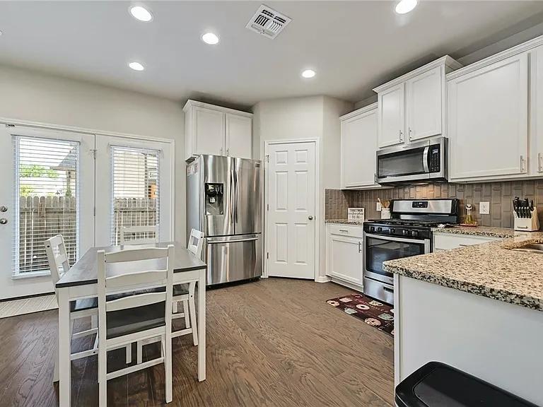 906 Boatswain Way Austin, TX 78748 - Photo 8 of 26 Kitchen featuring appliances with stainless steel finishes, light stone countertops, white cabinets, recessed lighting, and dark wood-style floors
