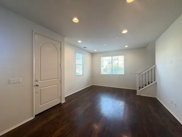 an empty room with wooden floor closet and windows