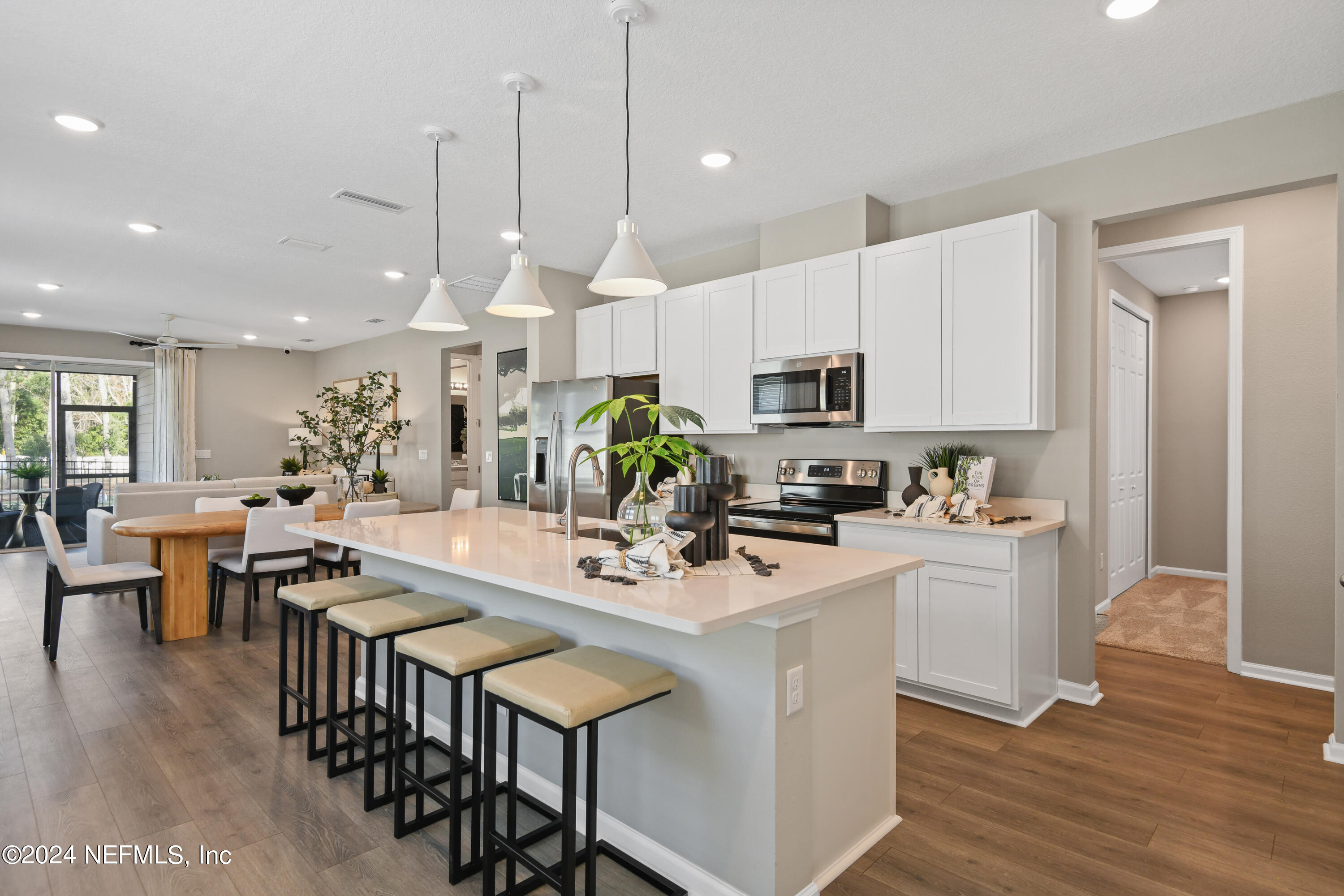 333 Cedar Elm Way St. Augustine, FL 32092 - Photo 4 of 24 a kitchen with stainless steel appliances kitchen island granite countertop a stove a sink a microwave a dining table and chairs