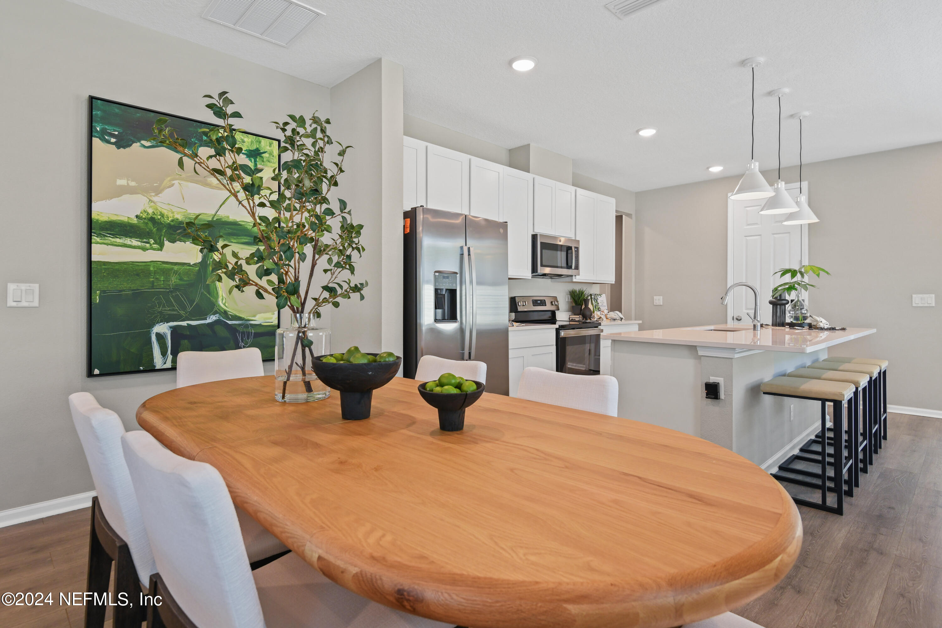 333 Cedar Elm Way St. Augustine, FL 32092 - Photo 7 of 24 a kitchen with stainless steel appliances a dining table chairs and couches with wooden floor