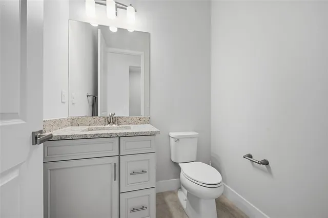 a bathroom with a granite countertop toilet sink and mirror