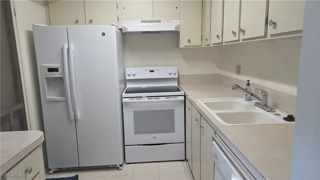 a white refrigerator freezer and a stove sitting inside of a kitchen