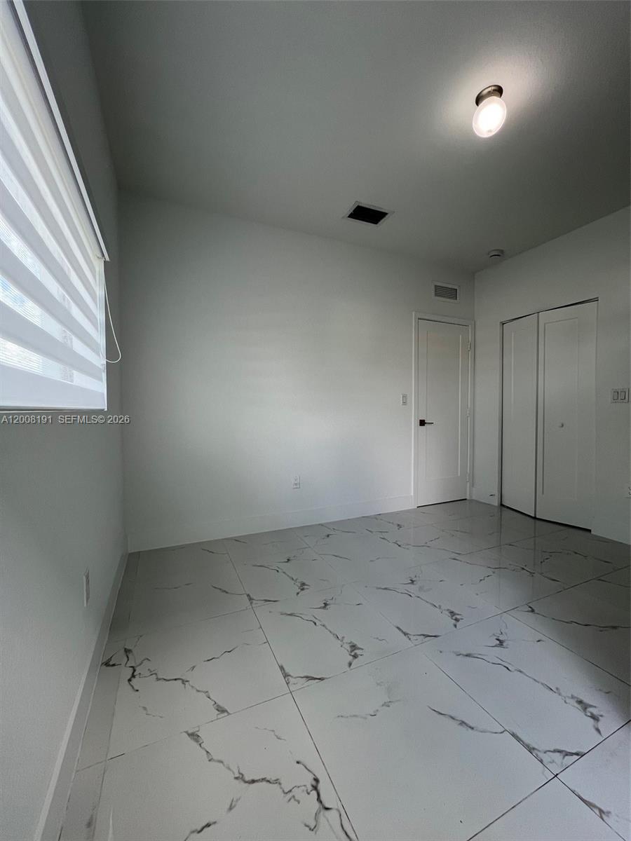 20007 Southwest 122nd Court, Unit 20007B Miami, FL 33177 - Photo 7 of 9 an empty room with white walls and windows