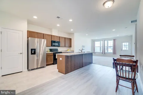 a kitchen with stainless steel appliances granite countertop a refrigerator a stove top oven and a dining table with wooden floor