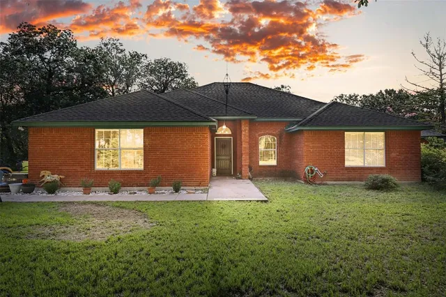a backyard of a house with table and chairs under an umbrella