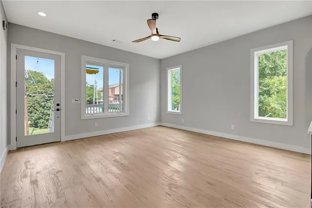 a view of an empty room with wooden floor and a window