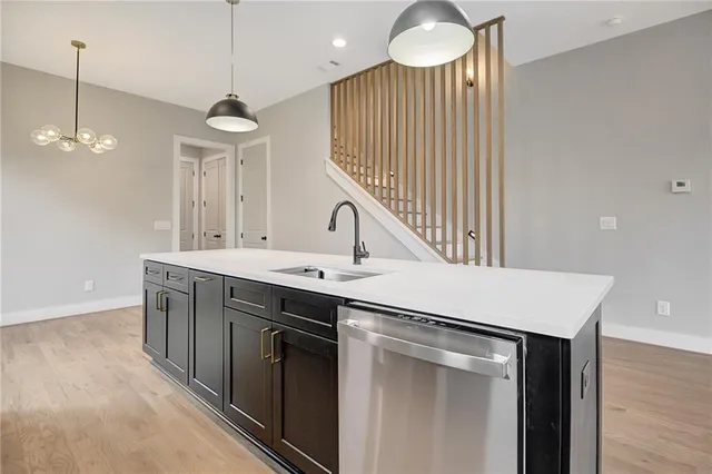 a kitchen with a sink a chandelier stainless steel appliances and cabinets