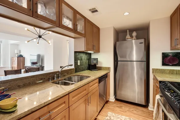 a kitchen with stainless steel appliances granite countertop a refrigerator a stove and a sink with wooden cabinets