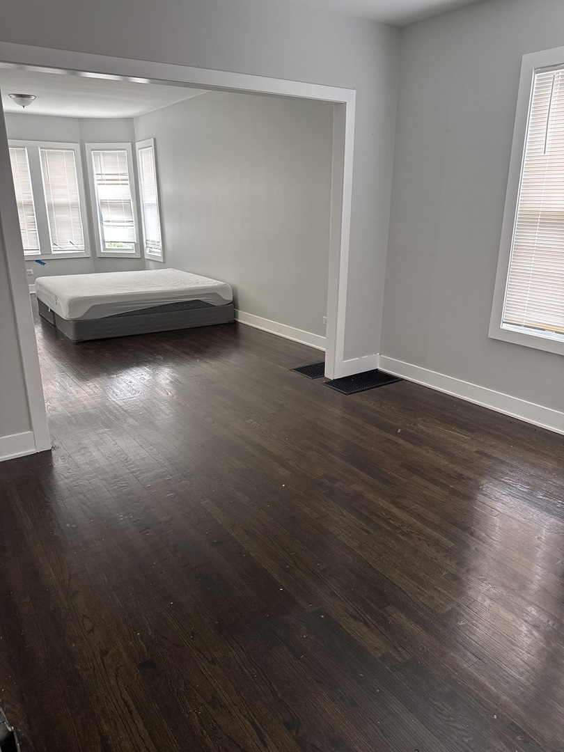 310 West 105th Street Chicago, IL 60628 - Photo 6 of 22 an empty room with wooden floor and windows