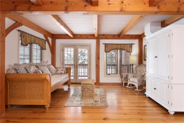 a living room with furniture large windows wooden floor and a table