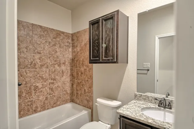 a bathroom with a granite countertop sink toilet and shower