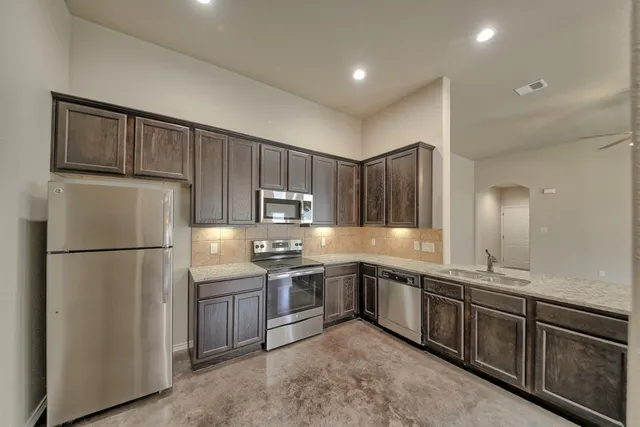 a kitchen with stainless steel appliances granite countertop a refrigerator a sink a stove a microwave and island