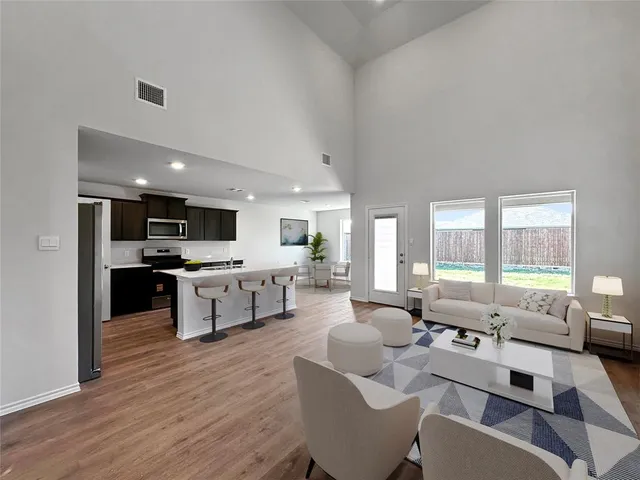 a large living room with stainless steel appliances kitchen island granite countertop a couch and white cabinets