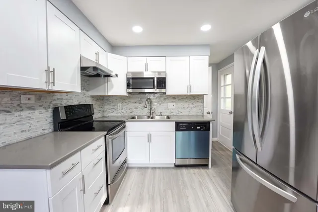 a kitchen with stainless steel appliances granite countertop a refrigerator sink and stove