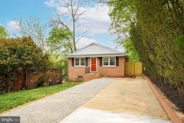 a front view of a house with a garden and trees
