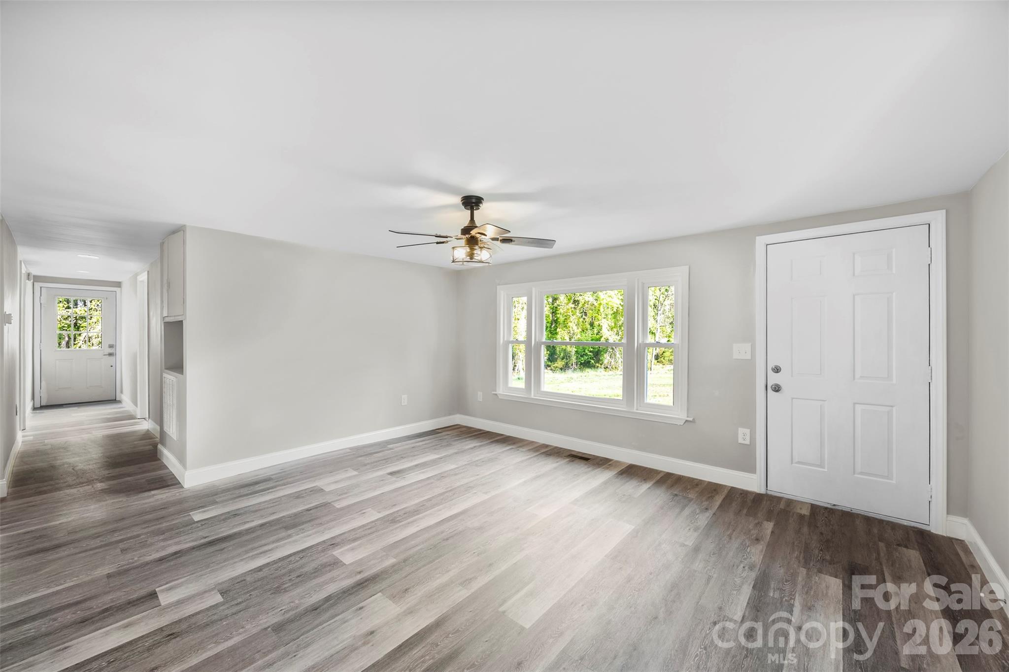 858 High Shoals Church Road Mooresboro, NC 28114 - Photo 3 of 25 an empty room with wooden floor chandelier fan and windows