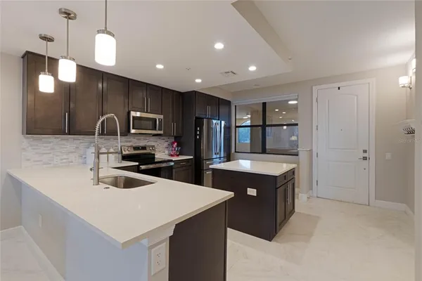 a kitchen that has a sink a center island stainless steel appliances and cabinets