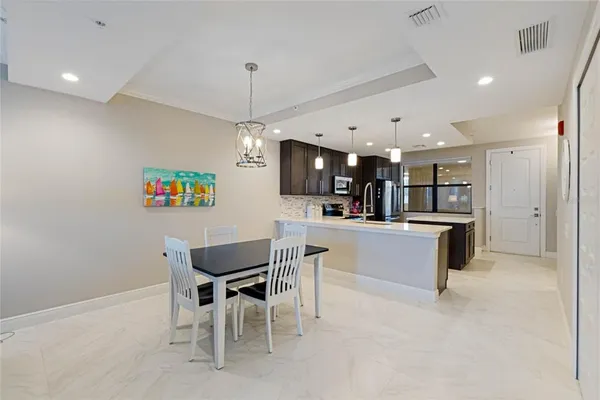 a kitchen with kitchen island a dining table chairs and a refrigerator